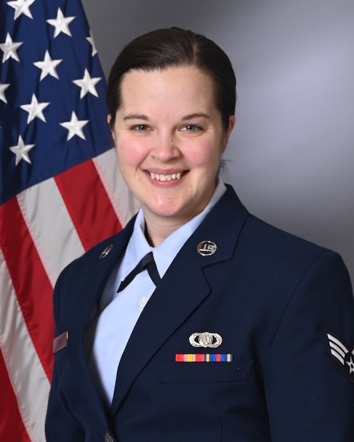 An official photo of Senior Airman Eliza Terry in front of the American flag wearing her service dress uniform.