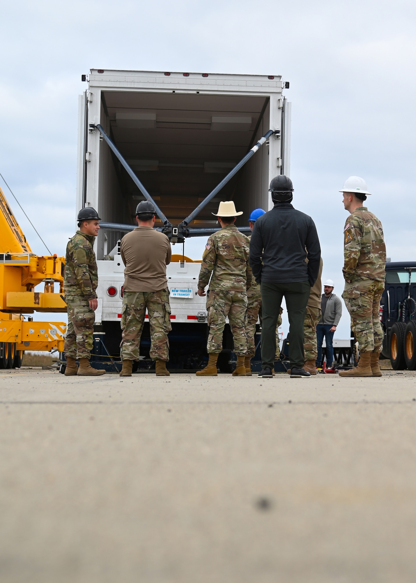 sls military members work in a transporter, big yellow cylinder test motor is pictured, and members are in hard hats