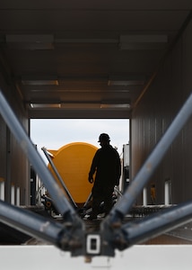 sls military members work in a transporter, big yellow cylinder test motor is pictured, and members are in hard hats