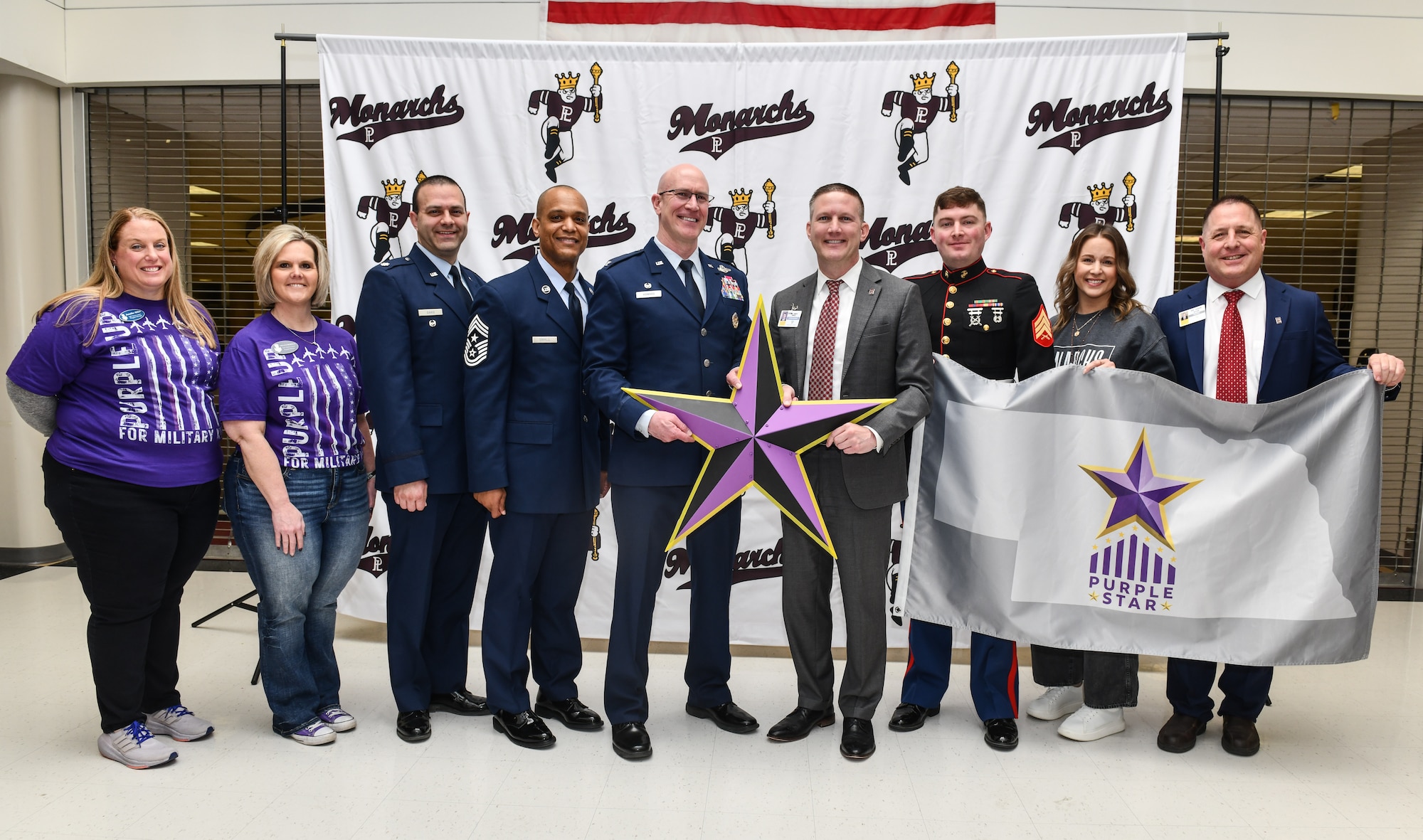 Col. Mark Howard, 55th Wing commander, and Dr. Andrew Rikli, Papillion La Vista Community School superintendent, pose with 55th Wing personnel and PLCS members at Papillion La Vista High School on April 11, 2025. A "Purple Star School" designation recognizes schools that demonstrate a strong commitment to supporting the unique needs of military-connected students and their families, often facing challenges due to frequent relocations and transitions. (U.S. Air Force photo by Chad Watkins)