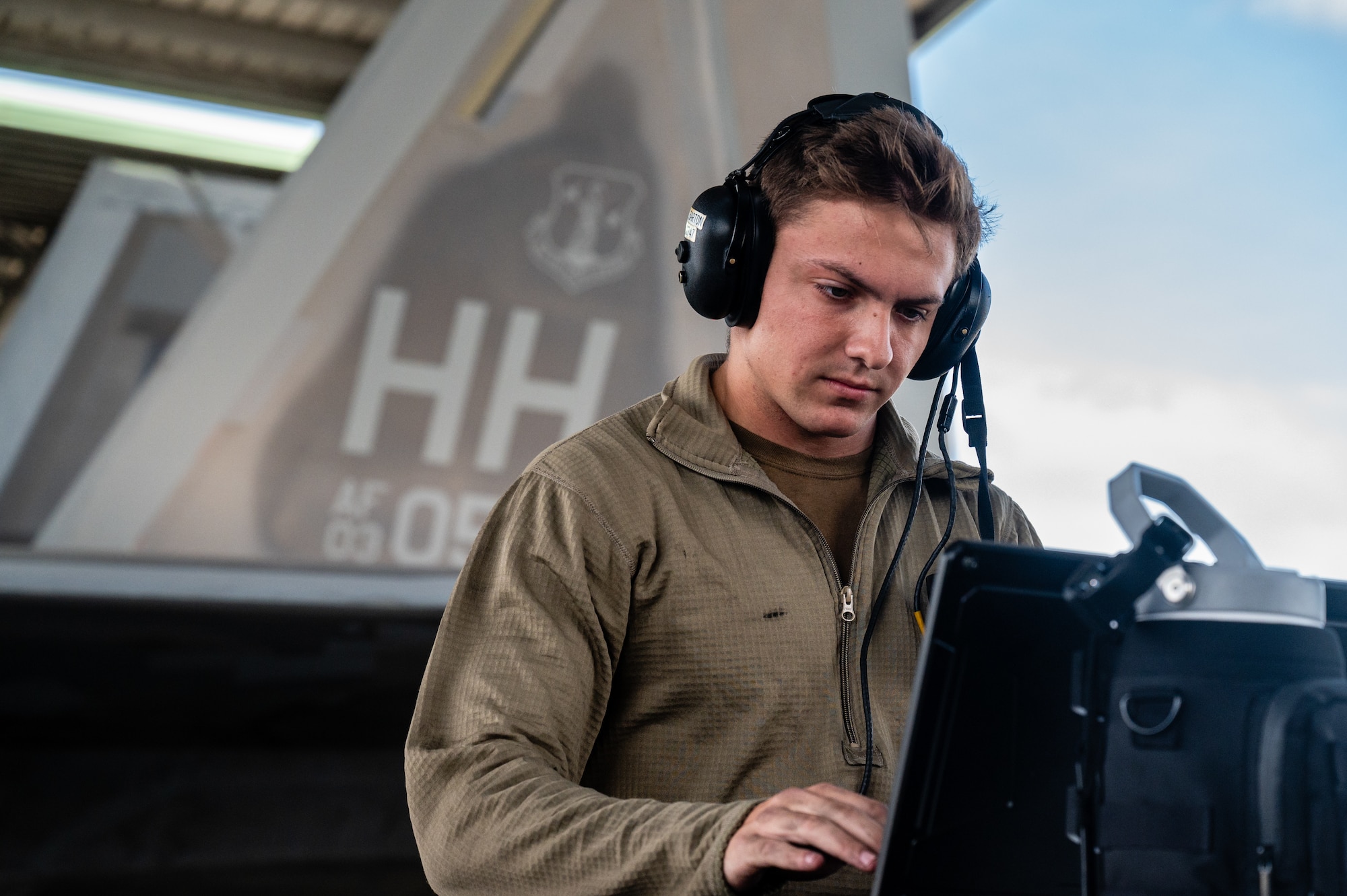 A crew chief utilizes his computer while performing flight prechecks on an F-22 Raptor.