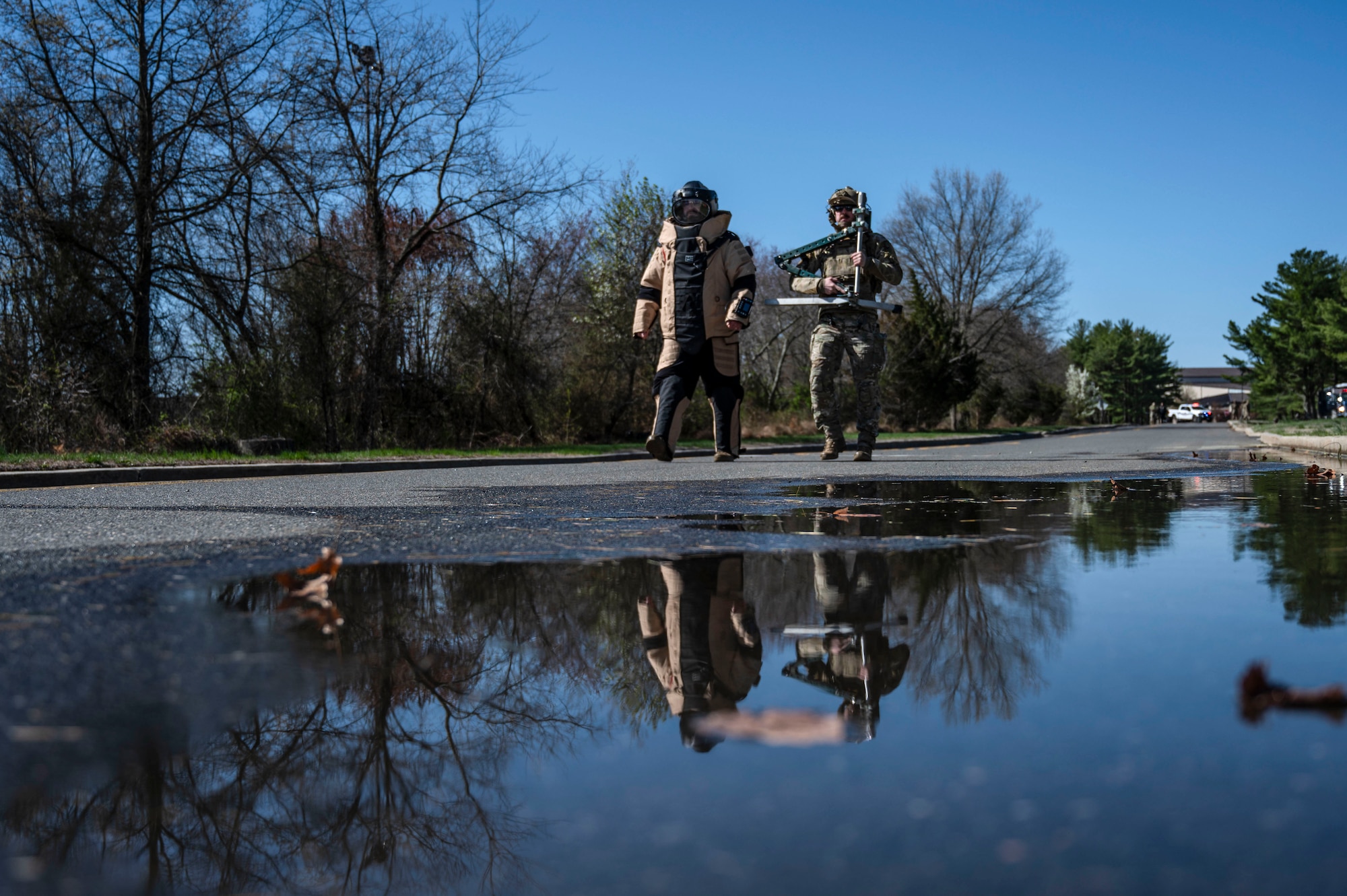 U.S. Air Force Tech. Sgt. Kenneth Maurer, 87th Explosive Ordnance Disposal section chief and Senior Airman Alexander Evans, 87th Explosive Ordnance Disposal team member walk to the water plant to safely disarm a fabricated ordnance during Operation Honey Badger (OHB) at Joint Base McGuire-Dix-Lakehurst, N.J., April 8, 2025. OHB is an exercise organized by the 87th Civil Engineer Squadron to prepare Airmen for real-world situations and promote mission readiness. (U.S. Air Force photo by Airman 1st Class Luisa E. Dugan)