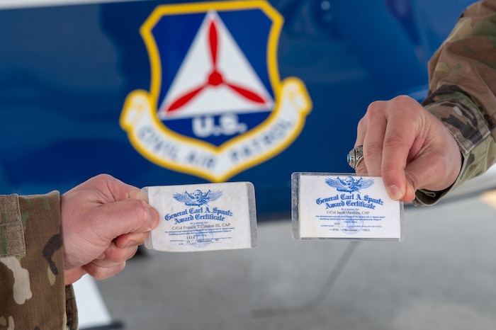 Image of two Airmen holding awards certificates.