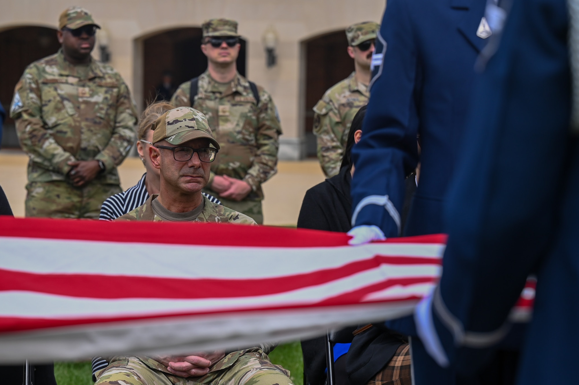 Photo of the Chief Master Sgt. of the Space Force sitting as Space Force Honor Guard members perform a flag folding demo in the foreground.