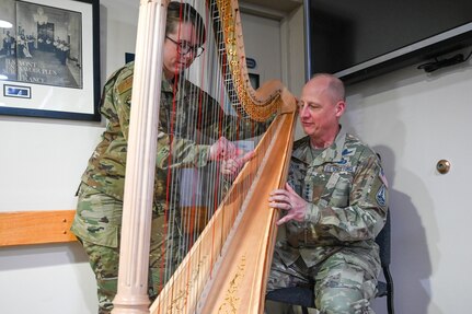 Photo of an Air Force Band harpist teaching the Vice Chief of Space Operations a chord on a harp.