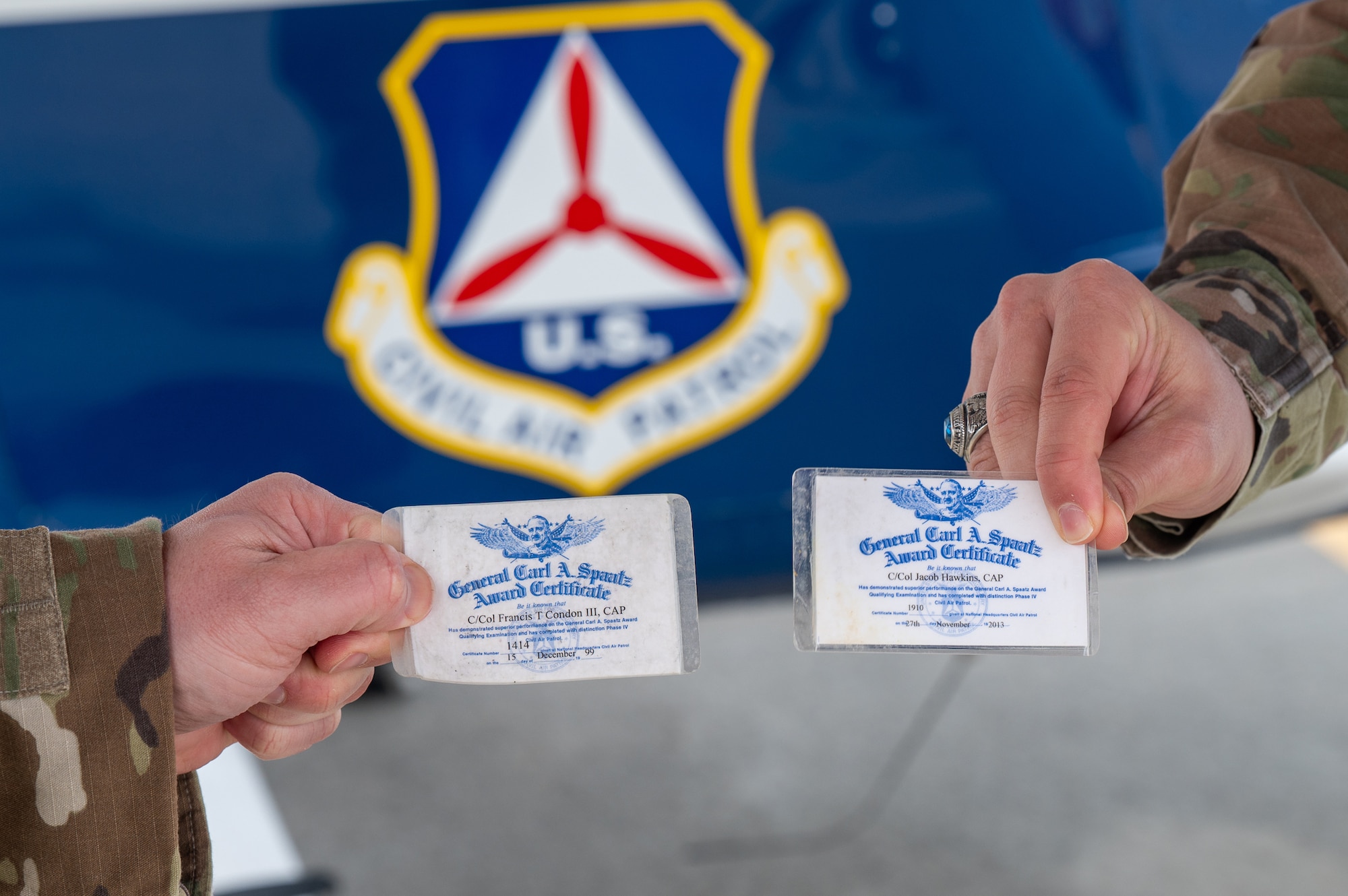 Image of two Airmen holding awards certificates.
