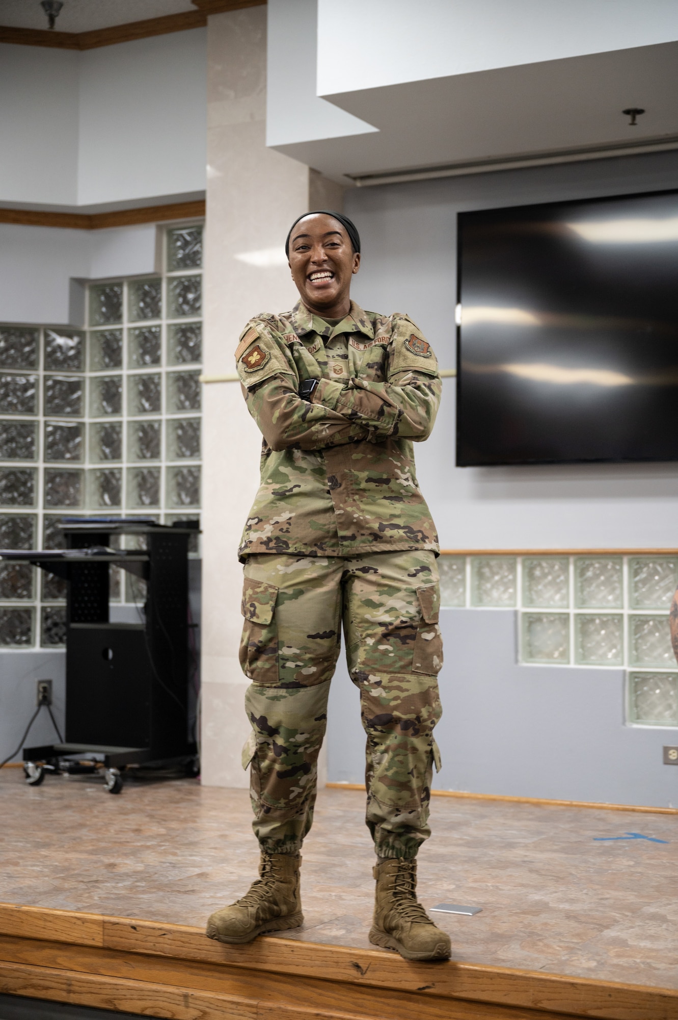 MSgt. Henderson stands on a stage and laughs while briefing trainees before their send off to basic military training.