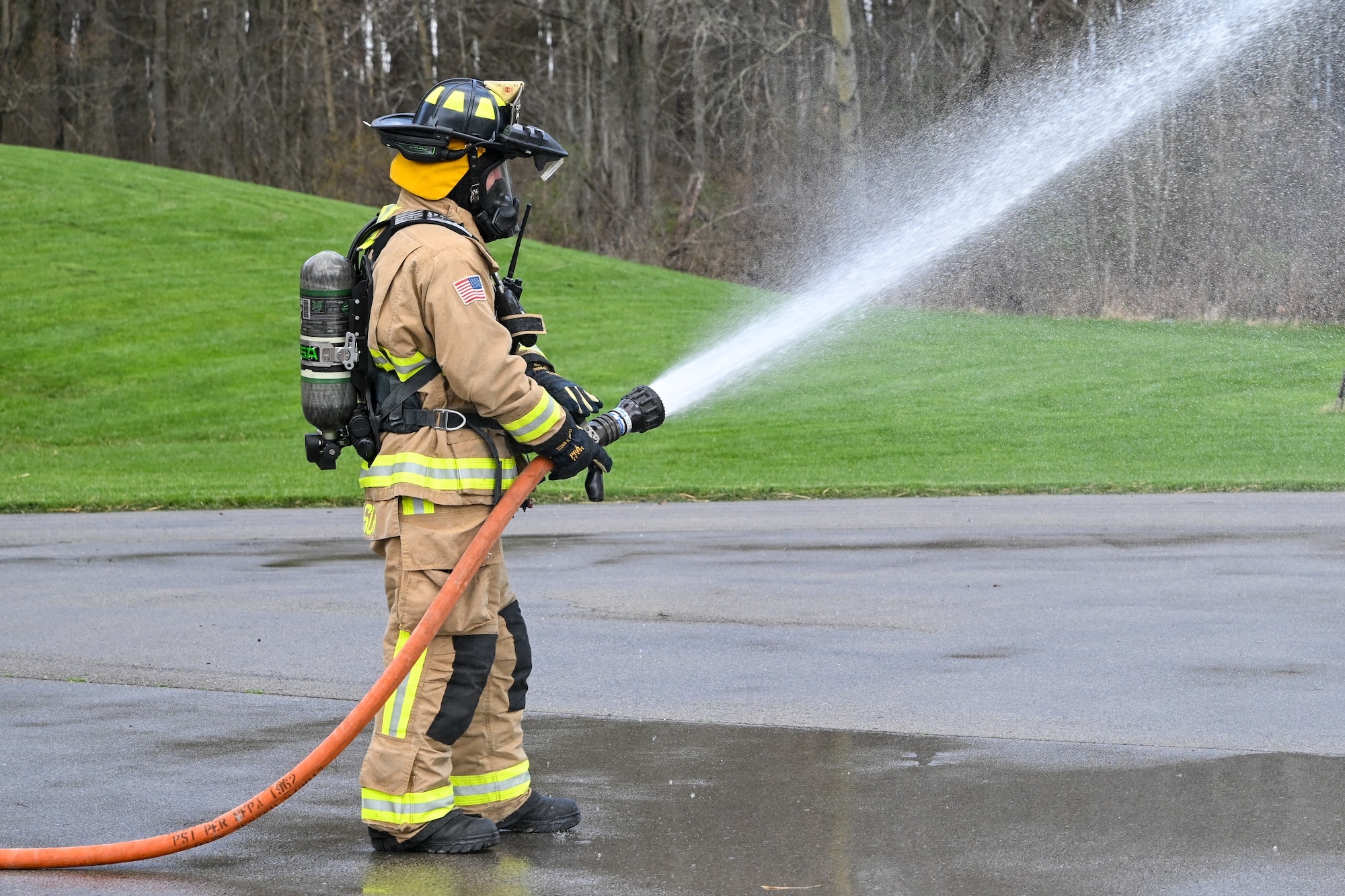 A firefighter equipped with an augmented reality helmet attachment system preps a hose before responding to a live-fire training event at YARS, Ohio, April 7, 2025.