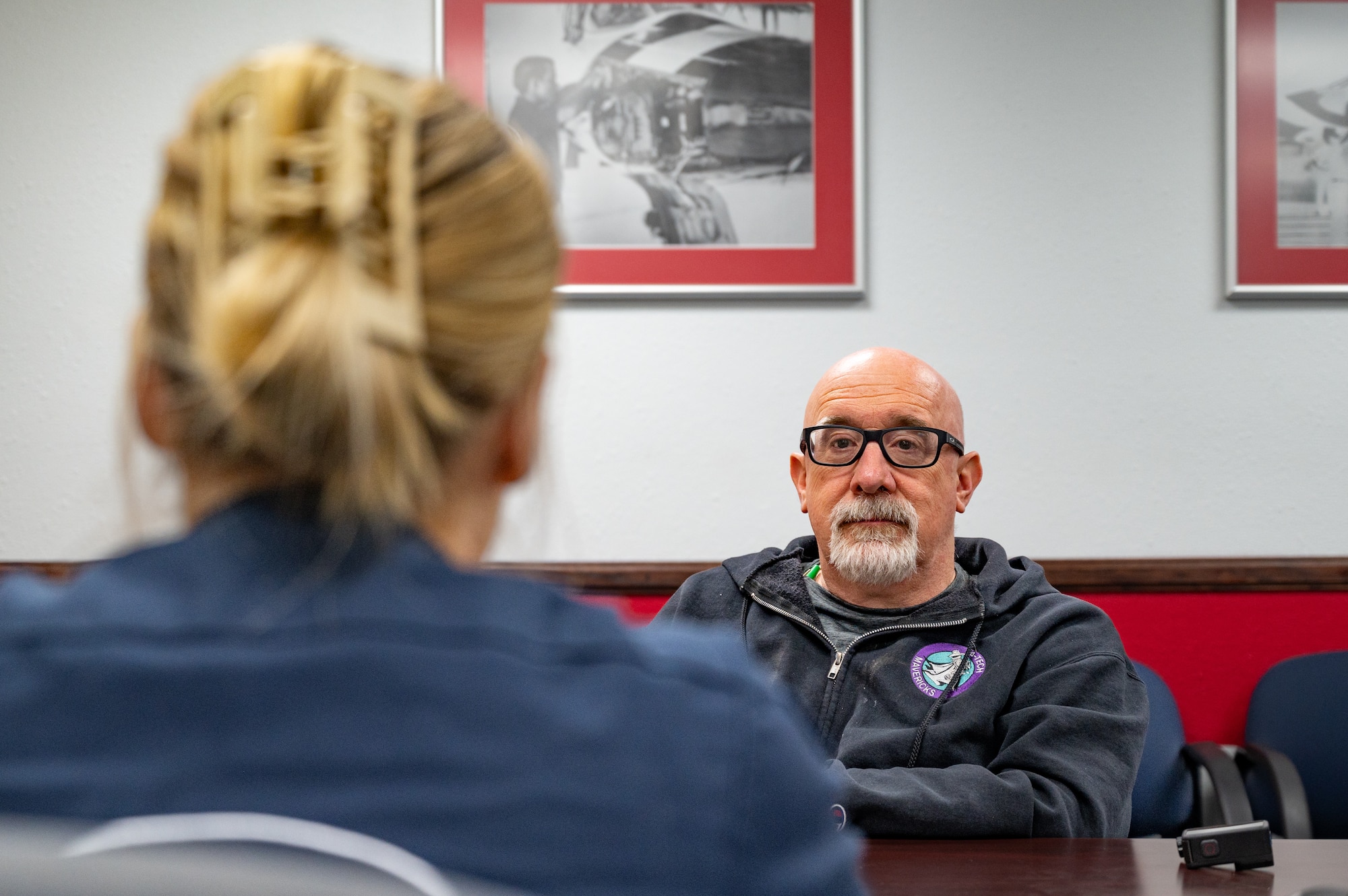 U.S. Air Force Senior Airman Lauren Clevenger, left, a public affairs specialist assigned to the Thunderbirds, briefs Hometown Hero participant, Michael Patterson, on the itinerary for the day on April 4, 2025 at Nellis Air Force Base, Nevada.