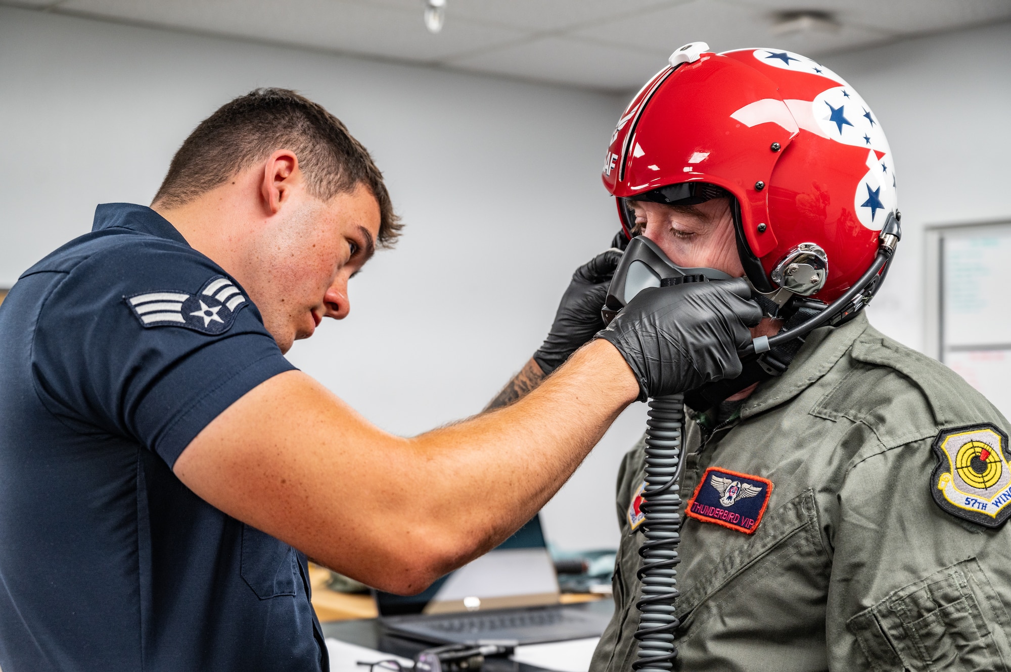U.S. Air Force Senior Airman Logan Pawson, left, shift lead and aircrew flight equipment specialist assigned to the Thunderbirds, secures a helmet on Michael Patterson, a participant of Hometown Hero, on April 4, 2025 at Nellis Air Force Base, Nevada.