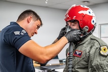U.S. Air Force Senior Airman Logan Pawson, left, shift lead and aircrew flight equipment specialist assigned to the Thunderbirds, secures a helmet on Michael Patterson, a participant of Hometown Hero, on April 4, 2025 at Nellis Air Force Base, Nevada.