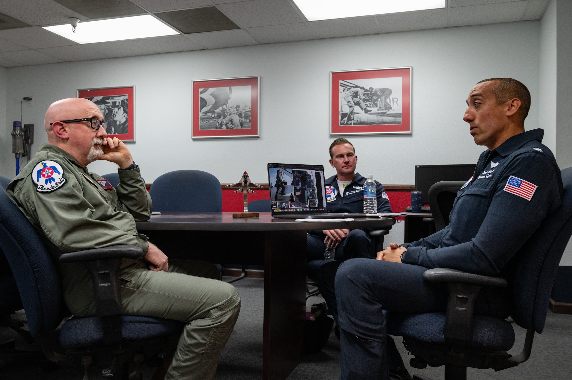 From left to right, Michael Patterson, Hometown Hero participant, U.S. Air Force Maj. Brandon Maxson, advance pilot and narrator assigned to the Thunderbirds and Lt. Col. Taylor Wight, an operations officer assigned to the Thunderbirds, discuss all maneuvers that will occur during the Hometown Hero flight, on April 4, 2025 at Nellis Air Force Base, Nevada.