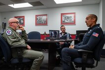 From left to right, Michael Patterson, Hometown Hero participant, U.S. Air Force Maj. Brandon Maxson, advance pilot and narrator assigned to the Thunderbirds and Lt. Col. Taylor Wight, an operations officer assigned to the Thunderbirds, discuss all maneuvers that will occur during the Hometown Hero flight, on April 4, 2025 at Nellis Air Force Base, Nevada.