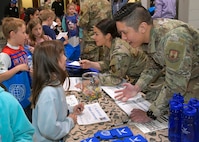 Airmen interact with students in a mock deployment line.