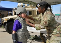 An Airman adjusts the chin strap of a helmet on a student.