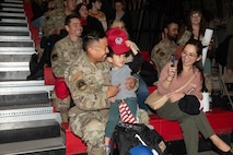 U.S. Air Force Senior Airman Chris Verzonilla, front left, assigned to the 820th Rapid Engineering Deployable Heavy Operations Repair Squadron Engineer (RED HORSE) Squadron, sits with his son and wife during a debrief during a redeployment at Nellis Air Force Base, Nevada, April 2, 2025.