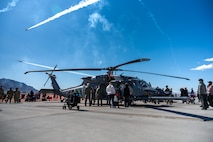 Guests at Aviation Nation 2025 explore inside an HH-60W Jolly Green II helicopter while the U.S. Air Force Thunderbirds perform an aerial display during Aviation Nation 2025 at Nellis Air Force Base, Nevada, April 4, 2025.