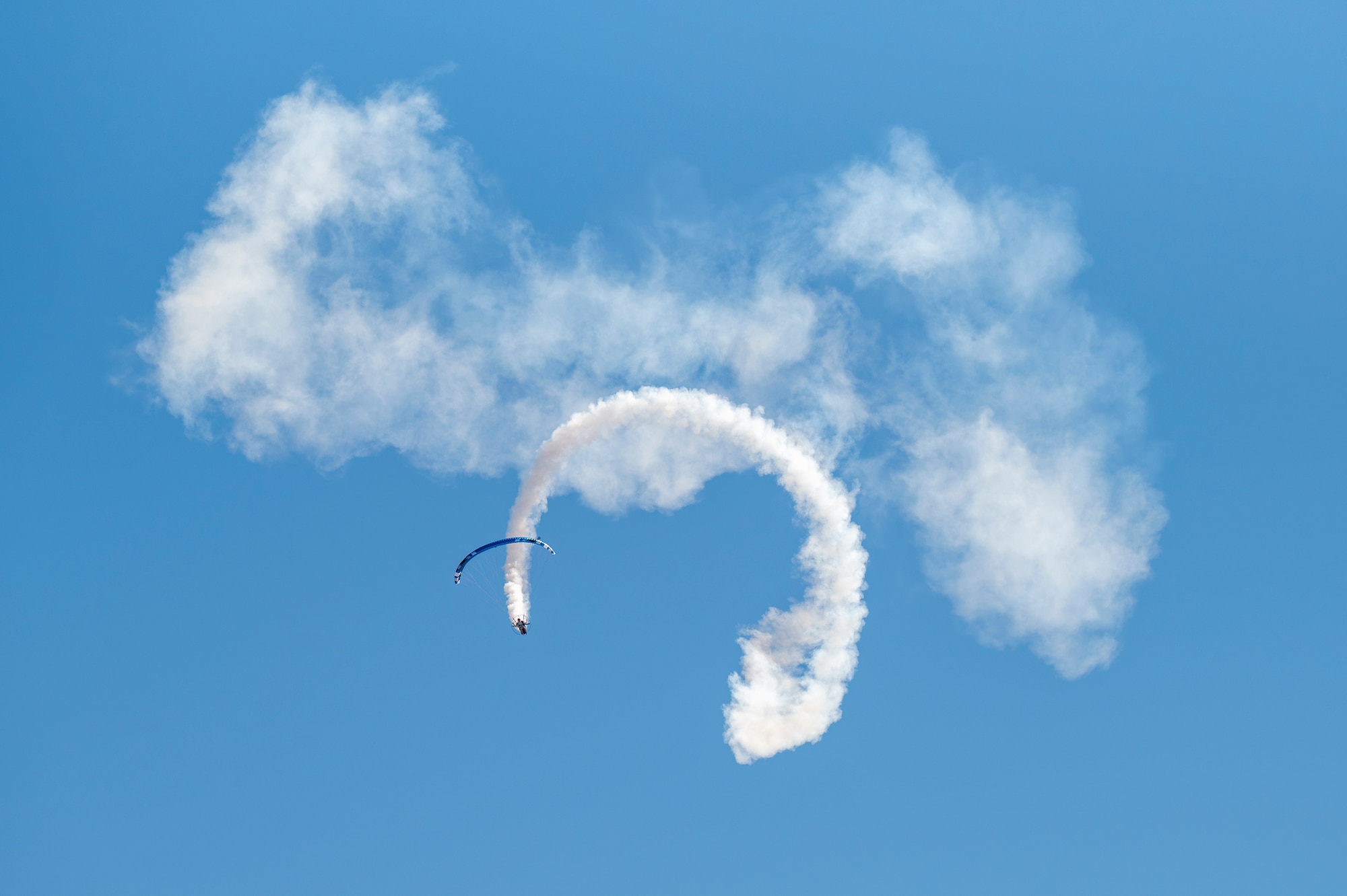 A paramotor parachutist leaves a trail of smoke while performing an aerial demonstration during Aviation Nation 2025 at Nellis Air Force Base, Nevada, April 5, 2025.