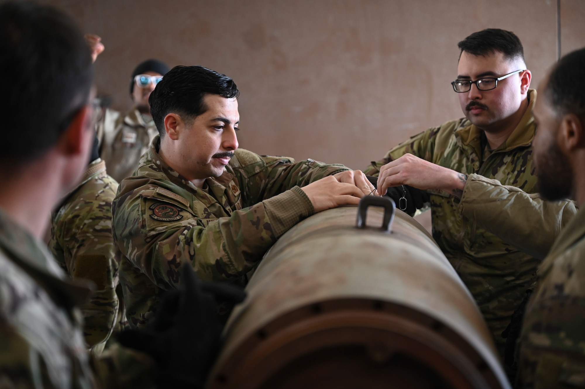 U.S. Air Force Staff Sgt. James Rogers III, 8th Maintenance Squadron Munitions Flight conventional maintenance crew chief, and Senior Airman Scott Thomas, 8th MXS Munitions Flight conventional maintenance crew chief, practice installing a charging receptacle well plug on a training munition.