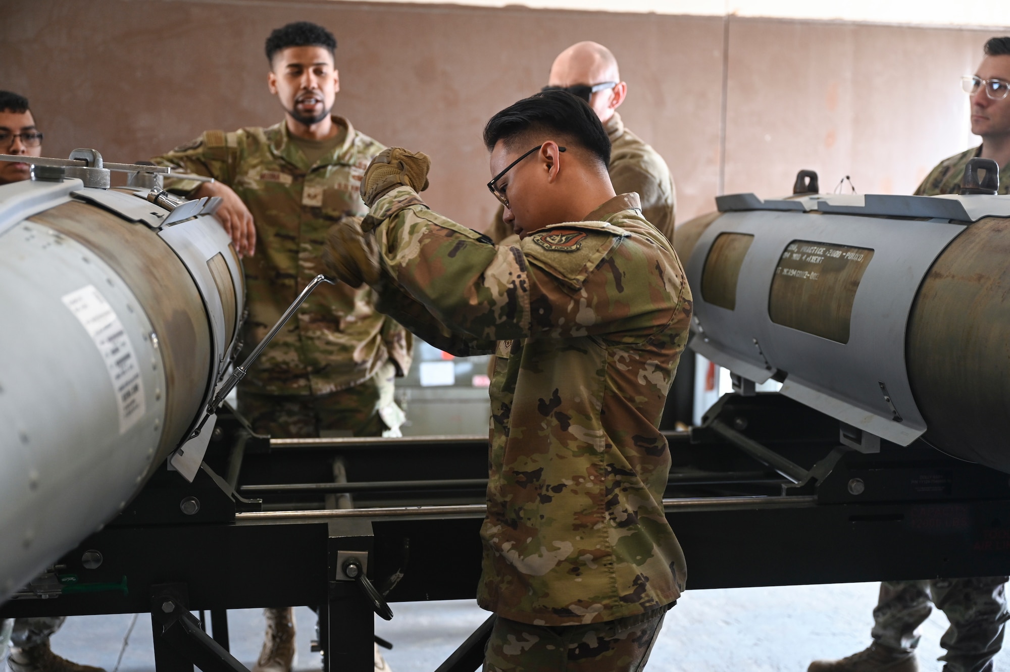 Airmen from the 8th Maintenance Squadron Munitions Flight tighten panels on a training munition.