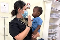 U.S. Air Force Staff Sgt. Jacqueline Candejas, 433rd Aeromedical Staging Squadron medical technician, entertains a child patient while the patient and their mother wait for lab test results at the New Amsterdam Public Hospital emergency room in New Amsterdam, Guyana, April 1, 2025.