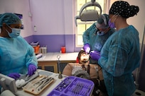 U.S. Air Force Col. Michael Dailey, Air Combat Command Surgeon General reserve expeditionary dentistry consultant, center, U.S. Air Force Master Sgt. Cassie Talley, 302nd Airlift Wing dental technician, right, and Christina Seenarine, Guyanese dental assistant, left, operate on a patient at the Port Mourant Hospital during the Lesser Antilles Medical Assistance Team mission in Port Mourant, Guyana, March 31, 2025.