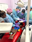U.S. Air Force Maj. Ross Johnson, 302nd Aeromedical Staging Squadron dentist, U.S. Air Force Master Sgt. Cassie Talley, 302nd Airlift Wing dental technician, and healthcare professionals from Port Mourant Hospital provide dental care to a child patient at the Port Mourant Hospital during the Lesser Antilles Medical Assistance Team mission in Port Mourant, Guyana, April 9, 2025.
