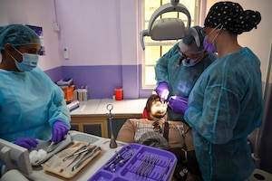 U.S. Air Force Col. Michael Dailey, Air Combat Command Surgeon General reserve expeditionary dentistry consultant, center, U.S. Air Force Master Sgt. Cassie Talley, 302nd Airlift Wing dental technician, right, and Christina Seenarine, Guyanese dental assistant, left, operate on a patient at the Port Mourant Hospital during the Lesser Antilles Medical Assistance Team mission in Port Mourant, Guyana, March 31, 2025.