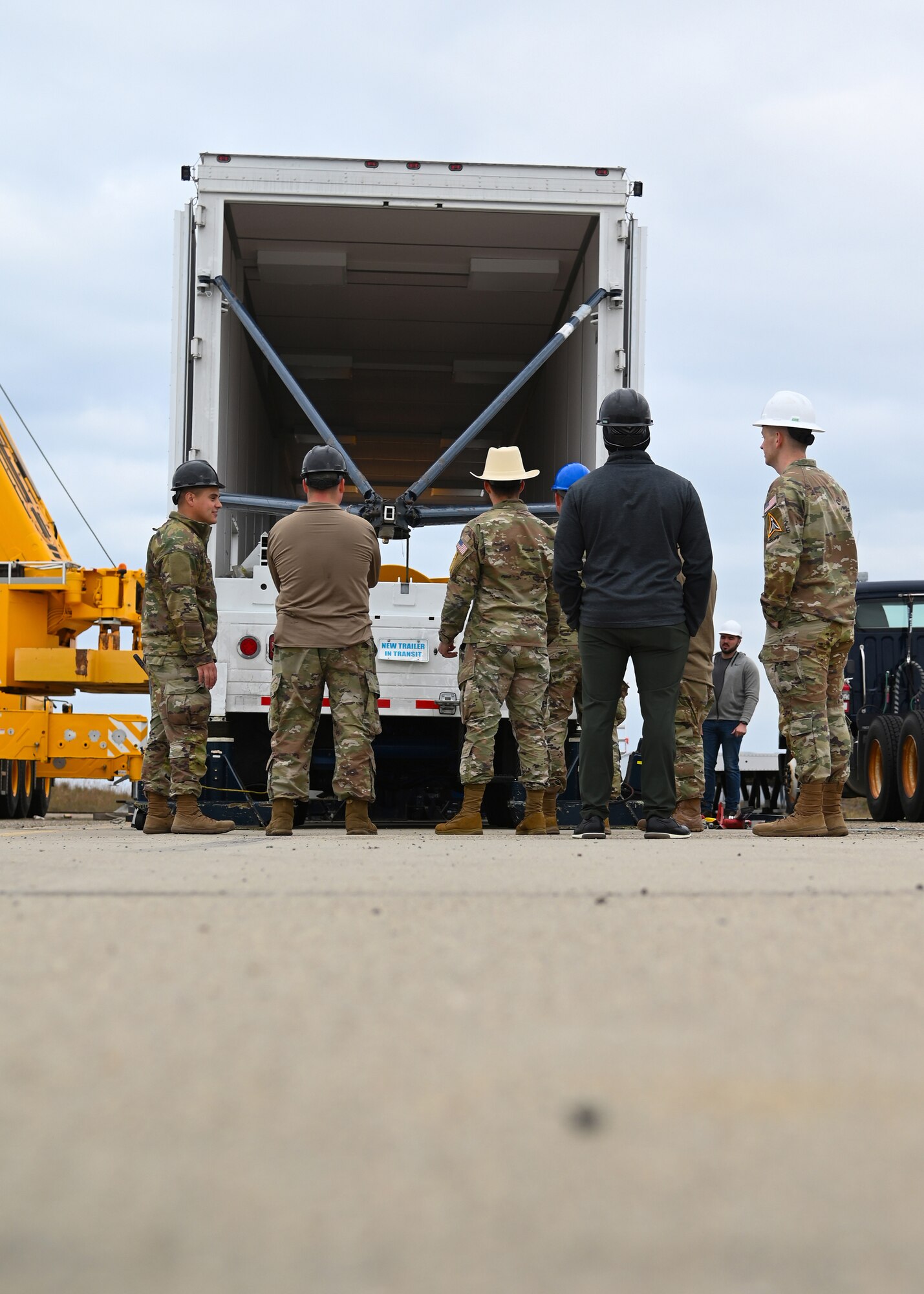 sls military members work in a transporter, big yellow cylinder test motor is pictured, and members are in hard hats
