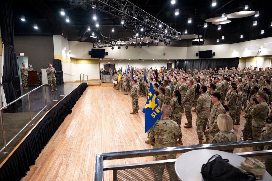 People stand off stage listening to a person talk.