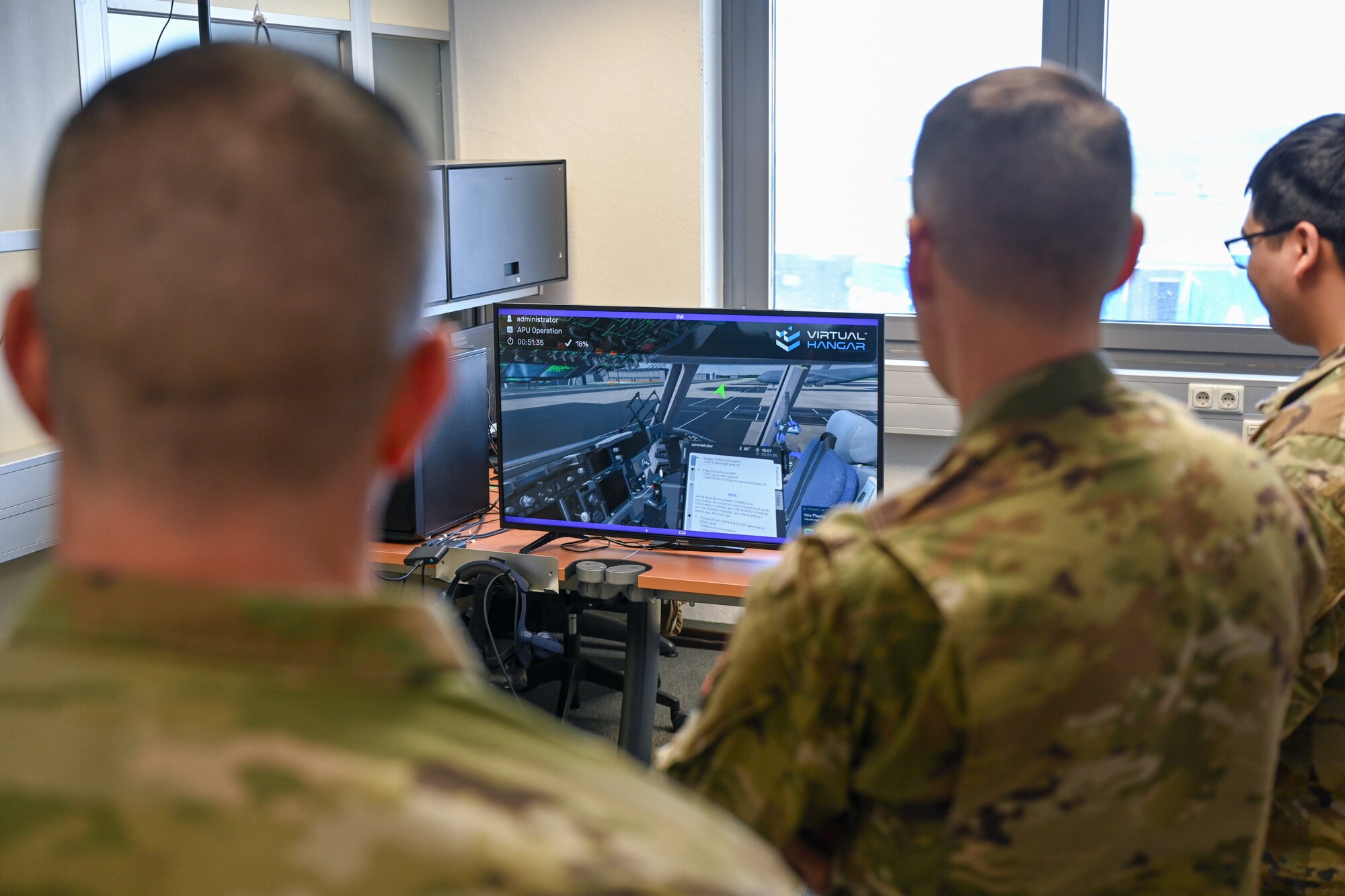 Brig. Gen. Stephen Snelson, center, U.S. Air Force Expeditionary Center commander, and Chief Master Sgt. Dennis Fuselier, left, USAFEC command chief, watch a Virtual Reality headset demonstration during an immersion tour with the 726th Air Mobility Squadron at the 726 AMS headquarters building on Spangdahlem Air Base, Germany, April 10, 2025.