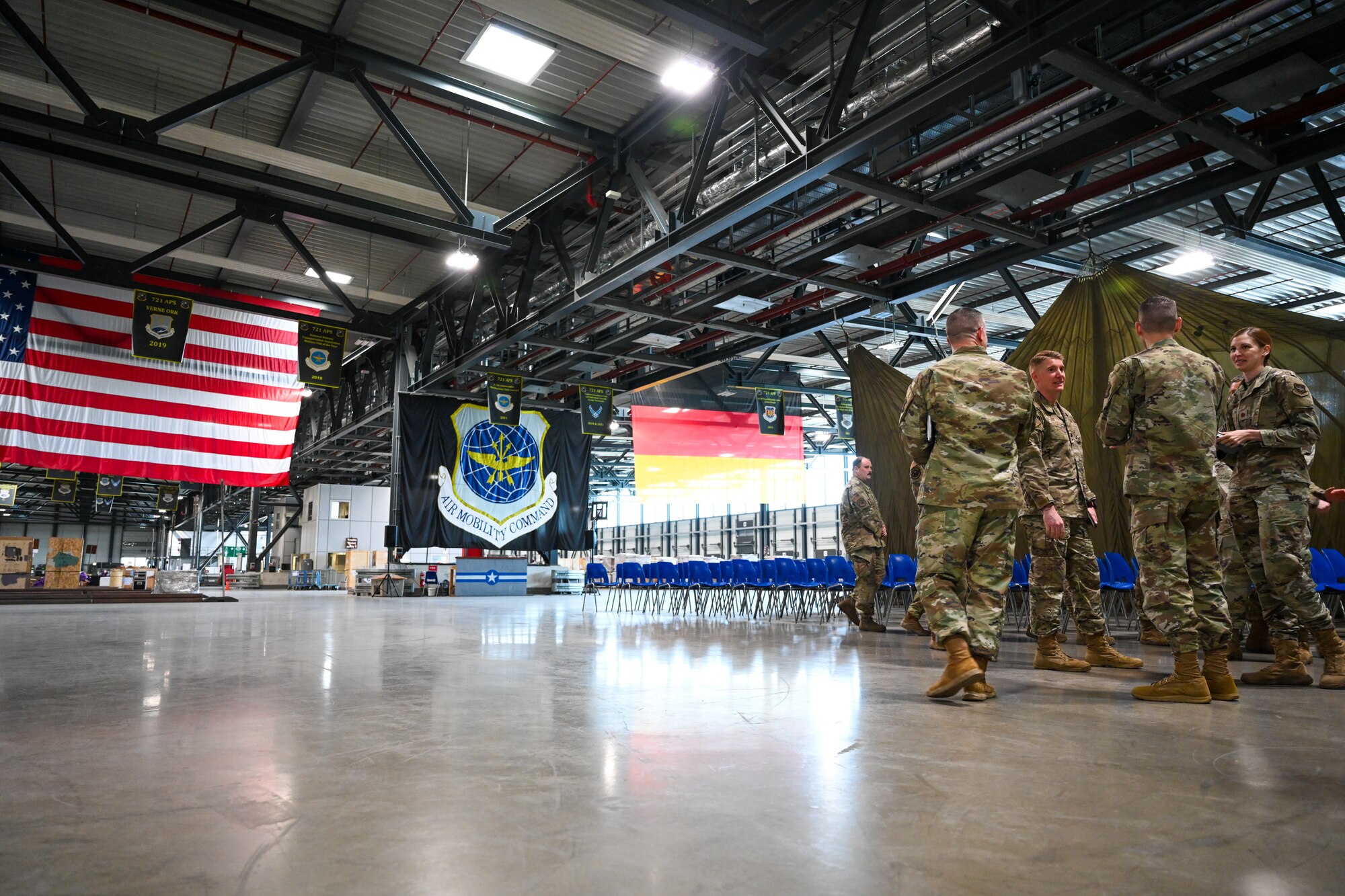 Brig. Gen. Stephen Snelson, U.S. Air Force Expeditionary Center commander, and Chief Master Sgt. Dennis Fuselier, USAFEC command chief, receives a brief from 721st Aerial Port Squadron leadership in the 721 APS throughput building on Ramstein Air Base, Germany, April 11, 2025.