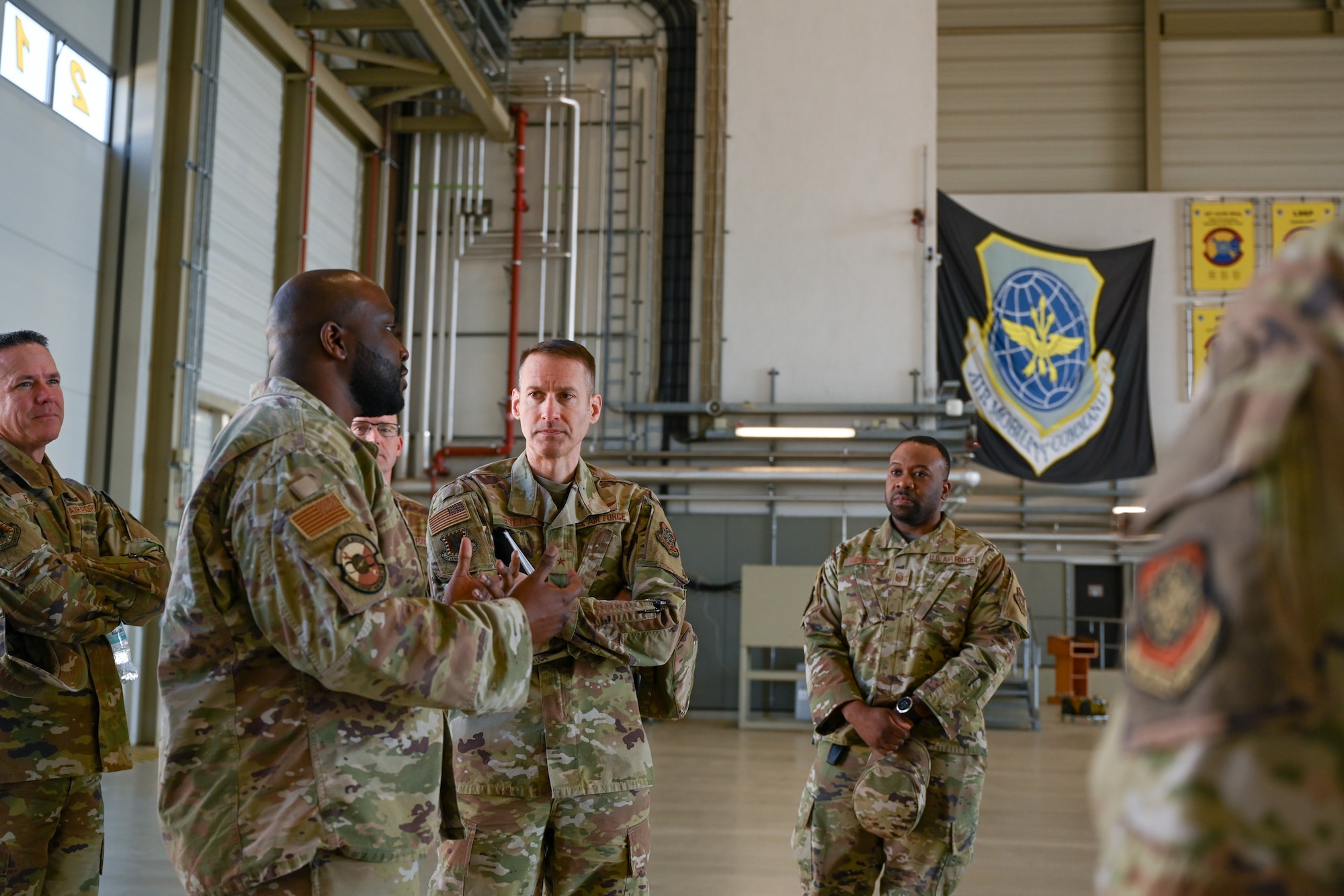 Brig. Gen. Stephen Snelson, center left, U.S. Air Force Expeditionary Center commander, receives a fuels brief from Tech. Sgt. Daren Jackson, left, 721st Aircraft Maintenance Squadron fuels NCOIC, in Hangar 5 on Ramstein Air Base, Germany, April 11, 2025.
