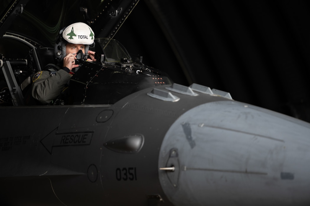 An F-16 pilot puts his mask on in an F-16.