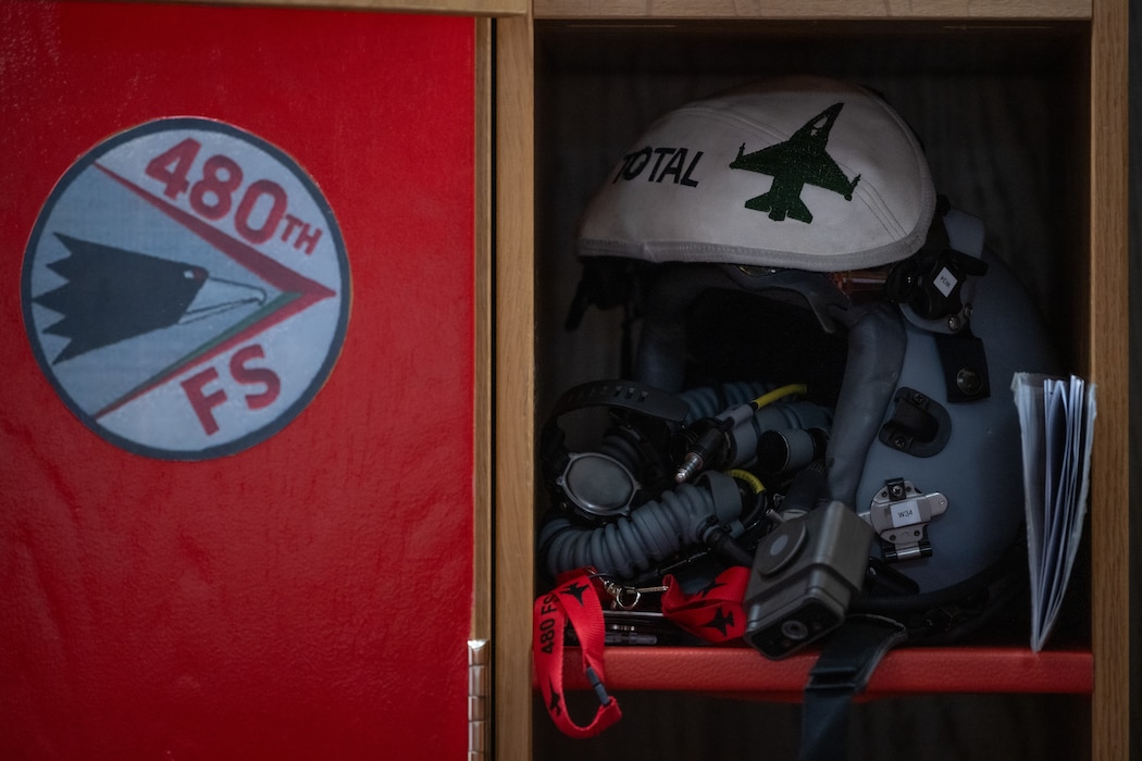 A pilot helmet sits in a locker.