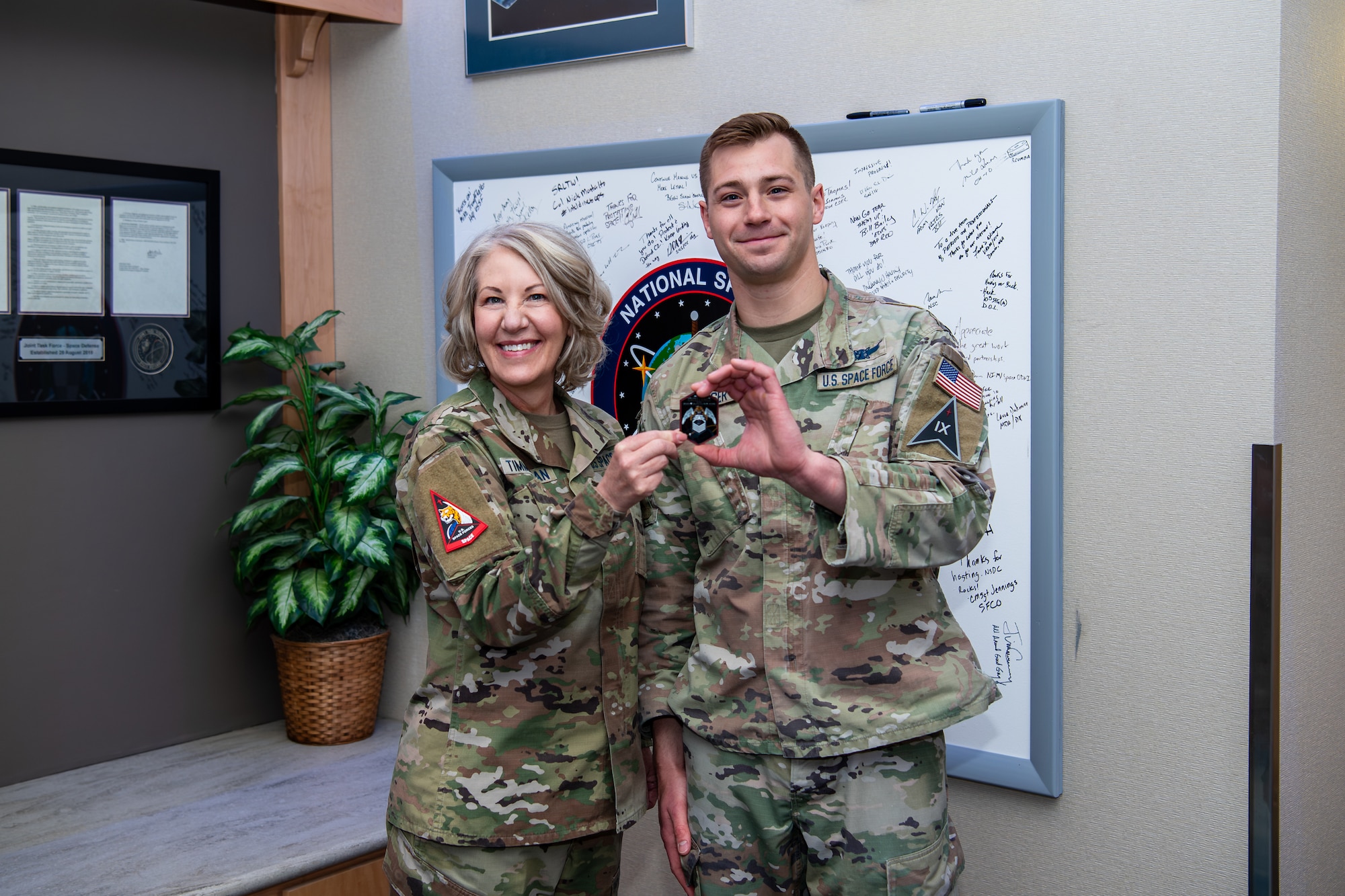woman in uniform holds coin with man in uniform