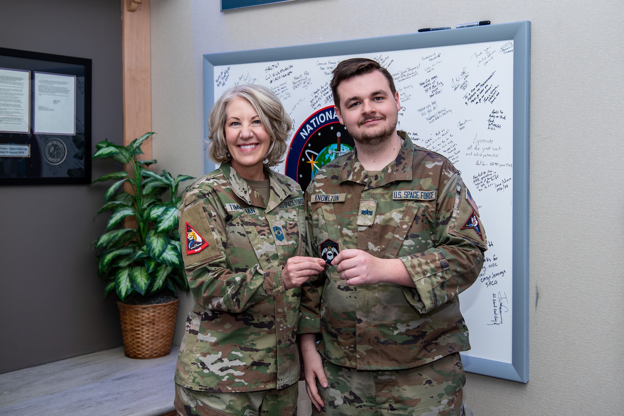 woman in uniform holds coin with man in uniform