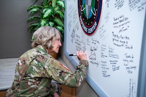 U.S. Space Force Chief Master Sgt. Tina Timmerman, left, U.S. Space-Forces Space Command Senior Enlisted Leader, signs the National Space Defense Center heritage board during a visit to the organization at Schriever Space Force Base, Colo., April 10, 2025. Timmerman visited the NSDC to recognize outstanding performers who went above and beyond during Apollo Griffin 25-1. (U.S. Space Force photo by Dalton Prejeant)