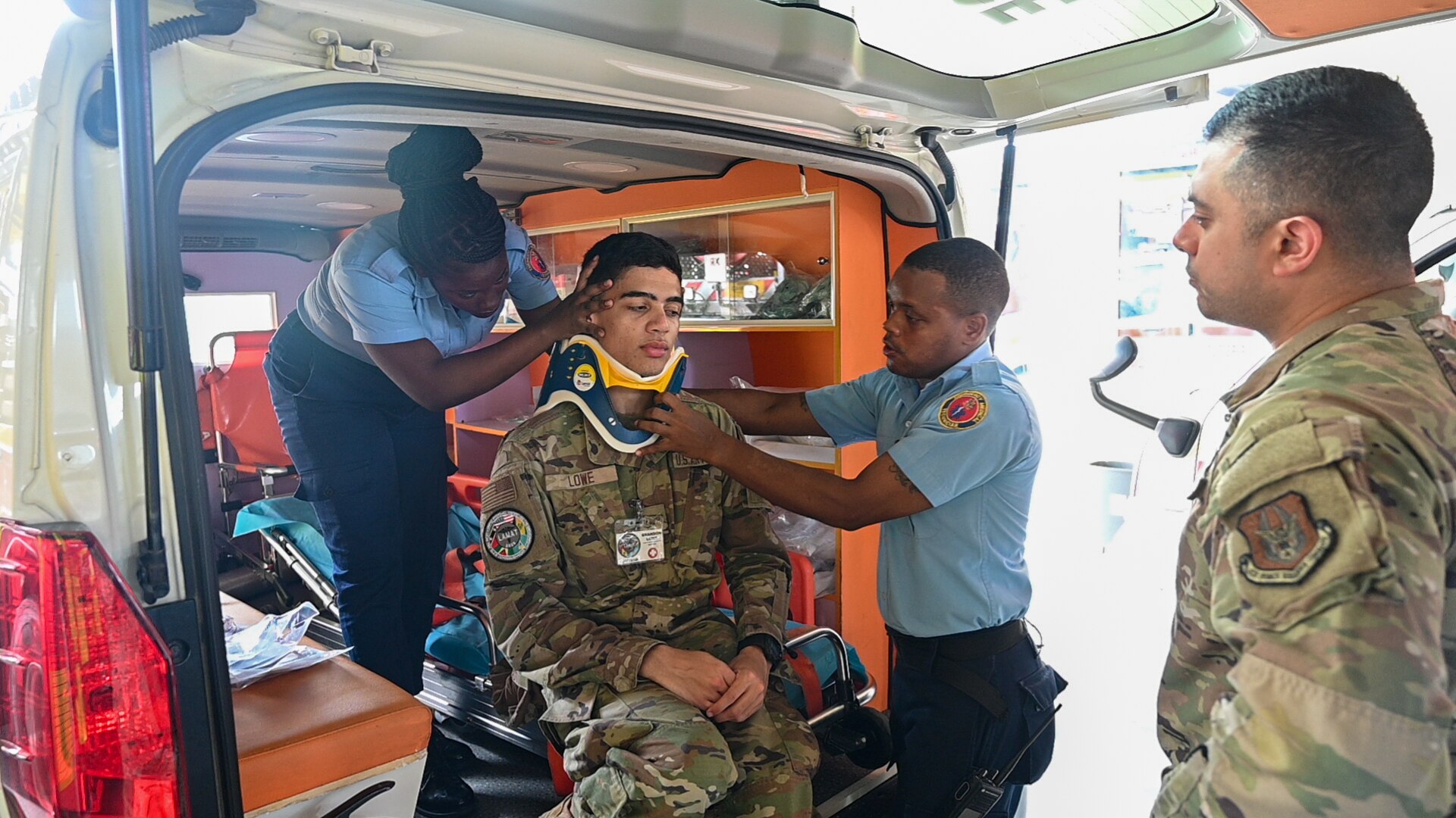 U.S. Air Force Tech. Sgt. Rodrigo Salinas and Senior Airman Brandon Lowe, both medical technicians with the 433rd Aeromedical Staging Squadron, learn how to apply a cervical collar inside an ambulance from Cleveland King, an advanced emergency medical technician training officer with the Guyana Fire and Emergency Medical Service, at the Guyana Fire Service Headquarters in Georgetown, Guyana, April 3, 2025. The training was part of the Lesser Antilles Medical Assistance Team mission, which brings together U.S. military medical personnel and local healthcare professionals from across Latin America and the Caribbean to exchange knowledge and strengthen partnerships.