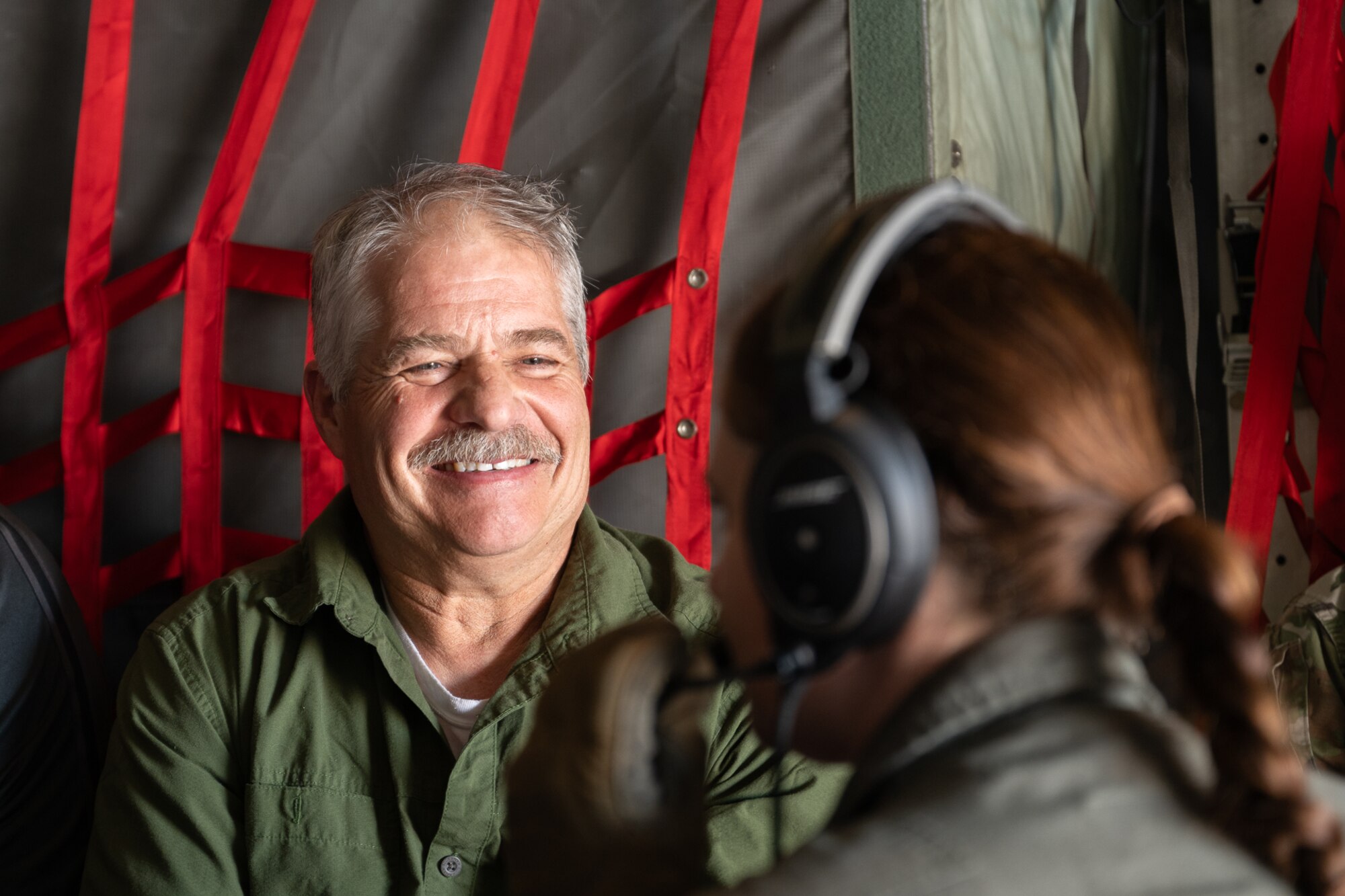 A man smiling at a woman wearing a headset and flight suit.