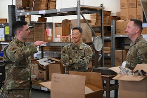 U.S. Air Force Staff Sgt. Matthew T. Haselden, noncommissioned officer in charge of outbound cargo with the 316th Logistics Readiness Squadron, speaks with Col. Jun S. Oh, 316th Wing and installation commander, and Chief Master Sgt. Kevin W. Helms, 316th Wing command chief, during a tour of Base Supply at Joint Base Andrews, Md., April 9, 2025. Haselden was recognized as part of the “Winnin’ Like a Griffin” program for his role in high-priority cargo movements supporting national-level missions. (U.S. Air Force photo by Senior Airman Gianluca Ciccopiedi)
