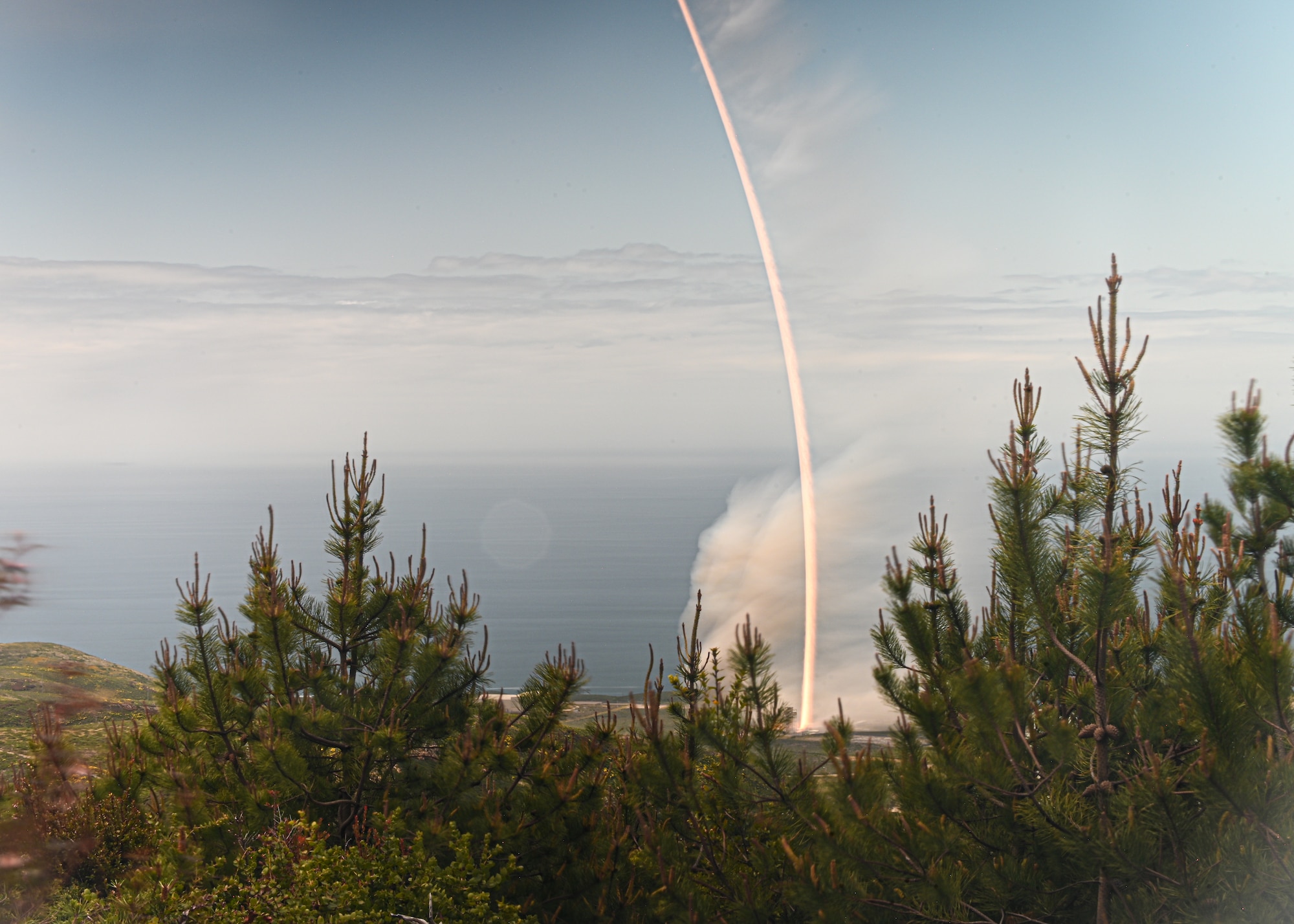 a rocket launches outside on the coastline.