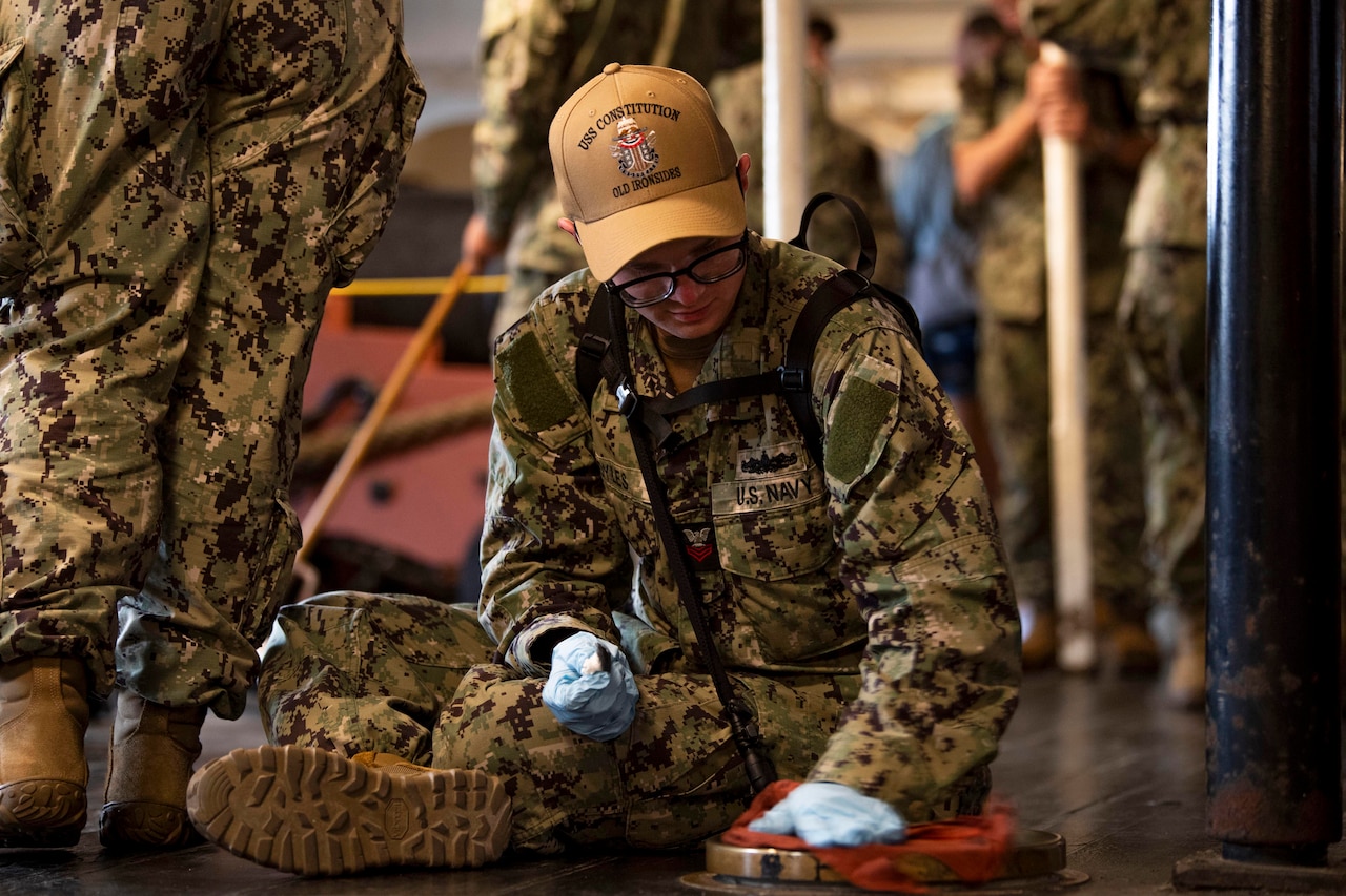 A sailor cleans the floor of a ship.