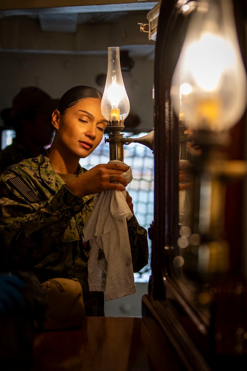 A sailor holds an old-fashioned lantern.
