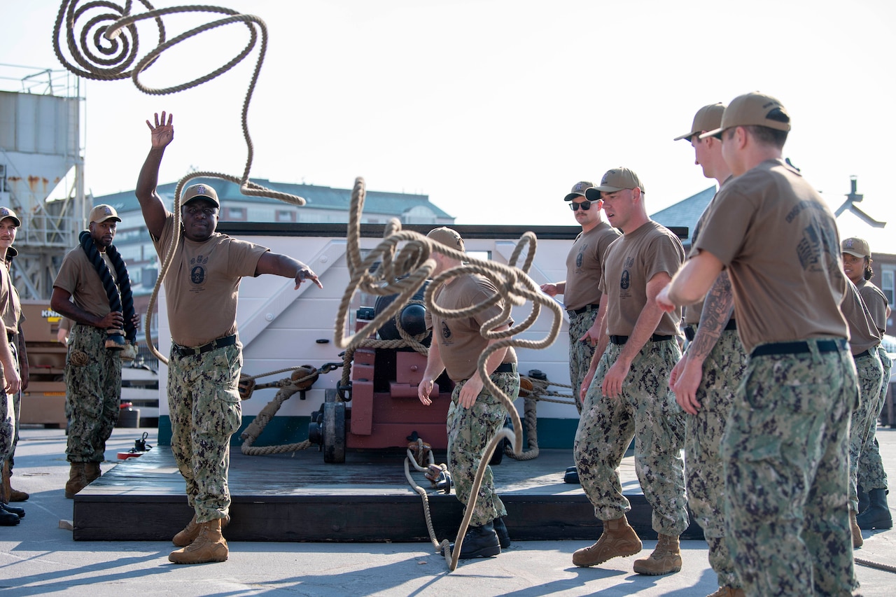 A group of sailors practice throwing ropes.