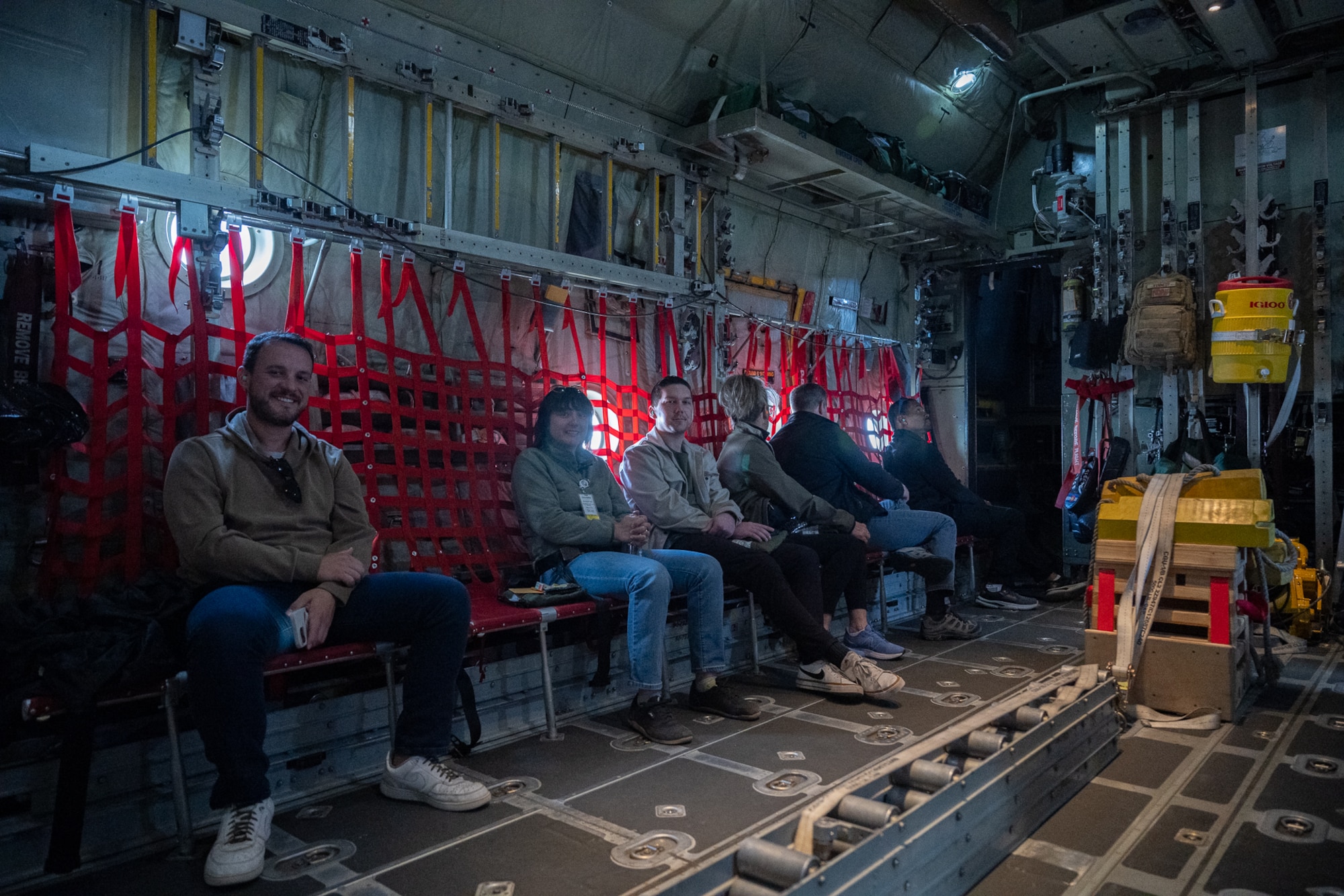 A group of people sitting in a chair in a military aircraft.