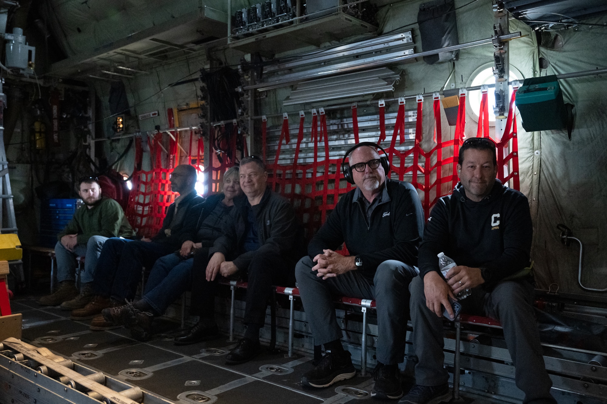 A group of people sitting in a chair in a military aircraft.