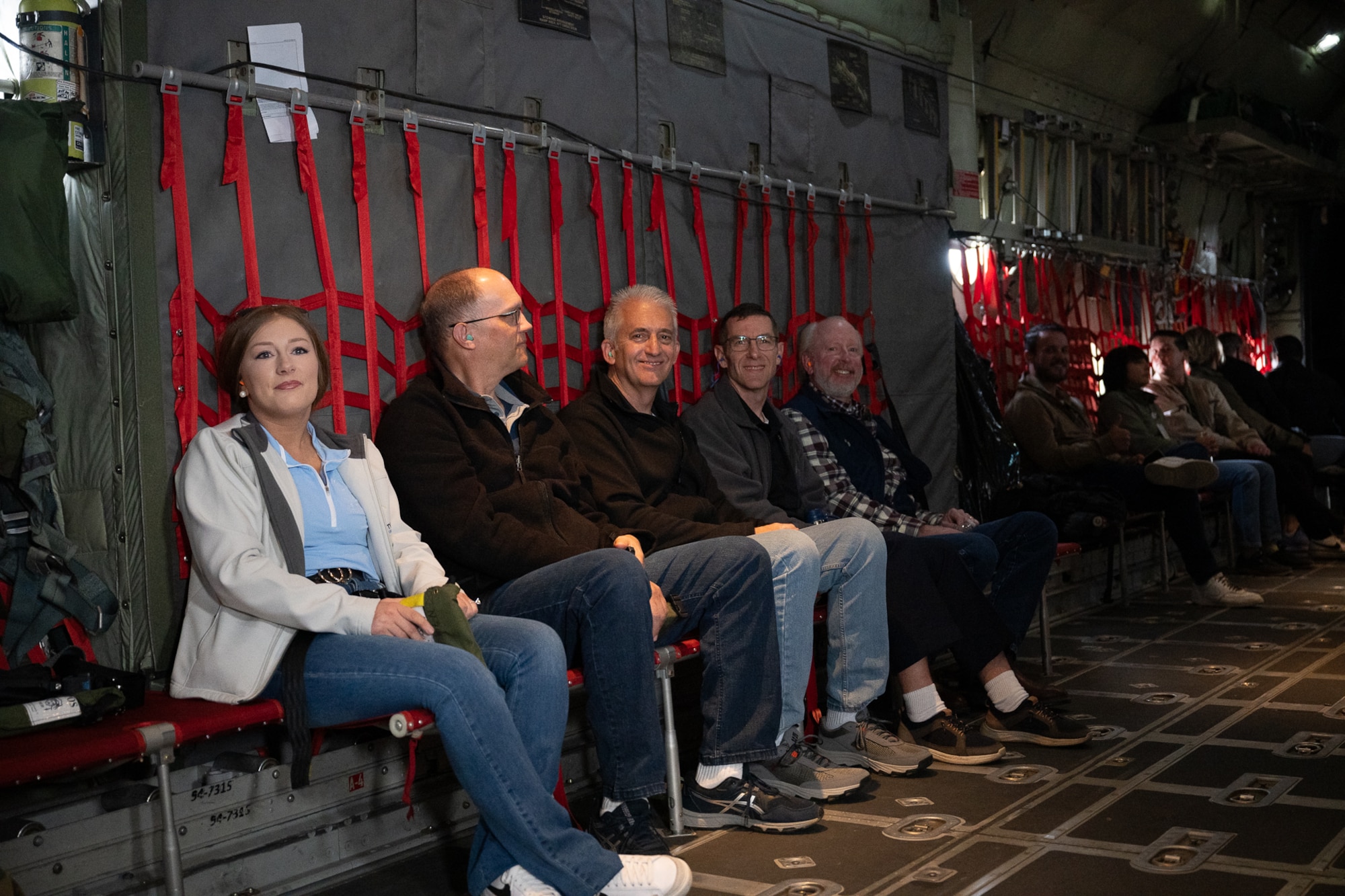 A group of people sitting in chairs in the back of a military aircraft.
