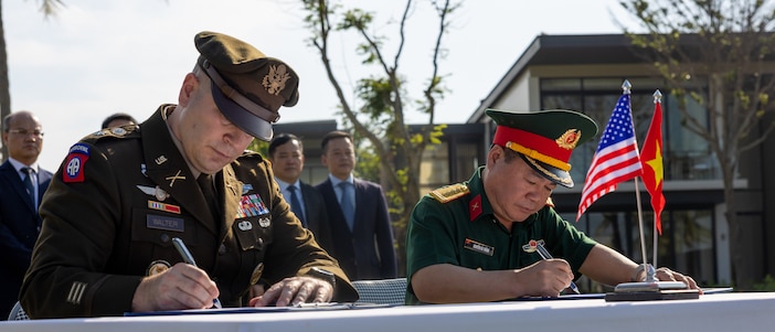 U.S. Army Lt. Col. Travis Walter, Defense POW/MIA Accounting Agency Detachment 2 commander, and General Nguyen Ba Thang, Vietnamese Office for Seeking Missing Persons, sign transfer documents before a repatriation ceremony in Vietnam, April 19, 2025.