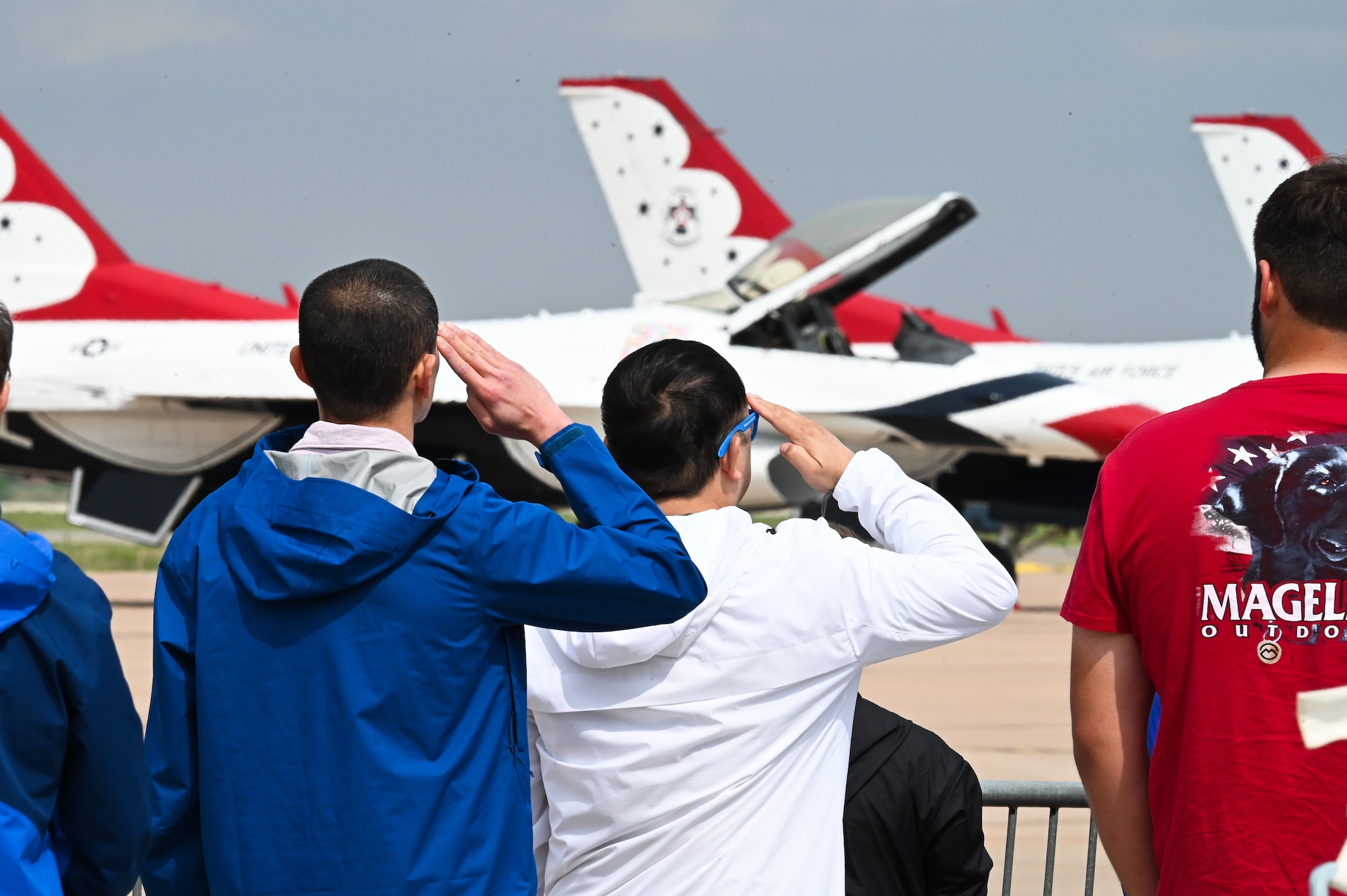 people salute during the national anthem in front of F-16 airplanes